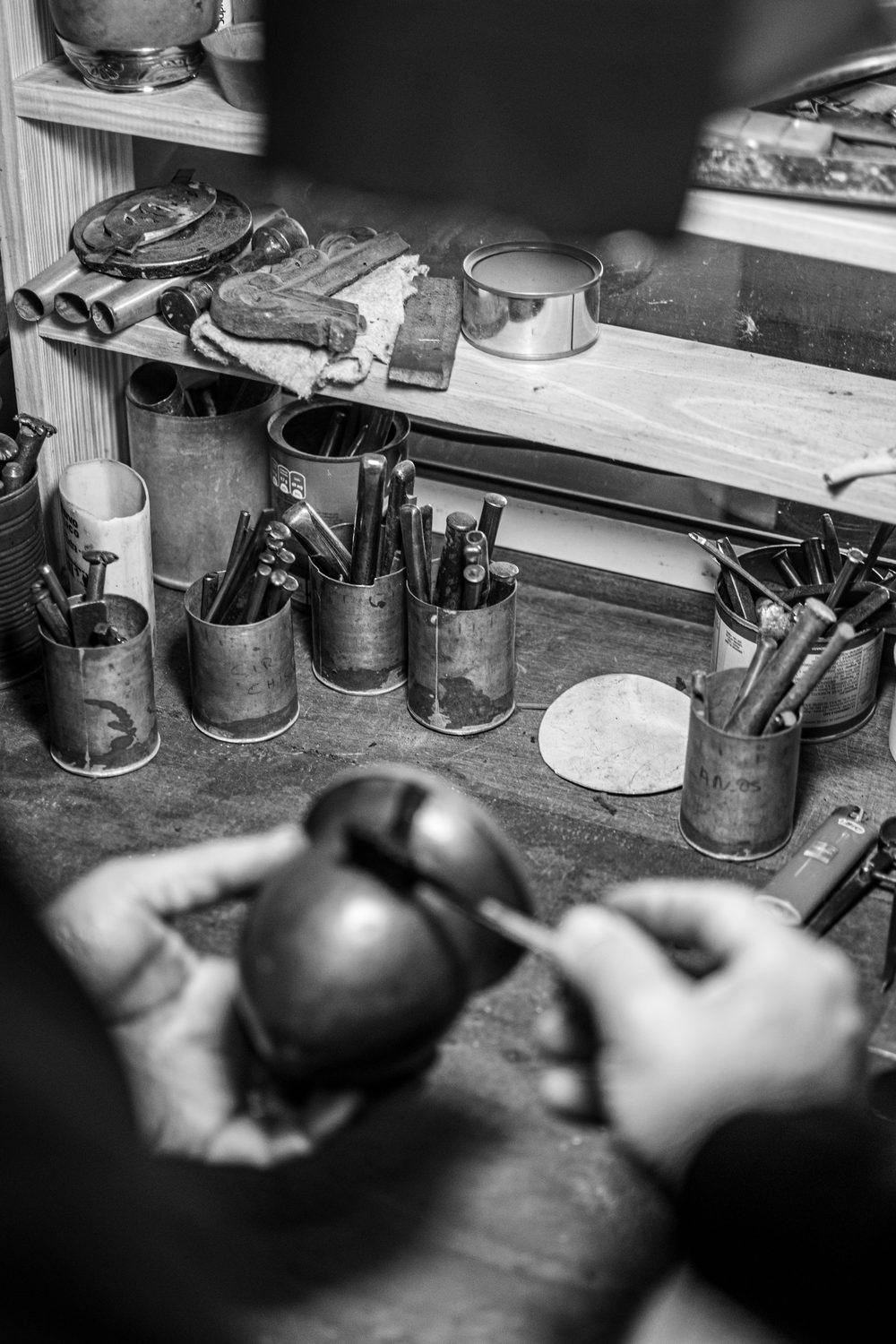 Manos trabajando una calabaza sobre la mesa de oficio, en blanco y negro